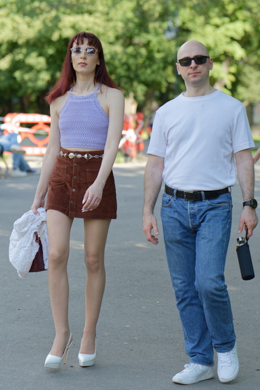 A couple of individuals strolling outdoors on a sunny day